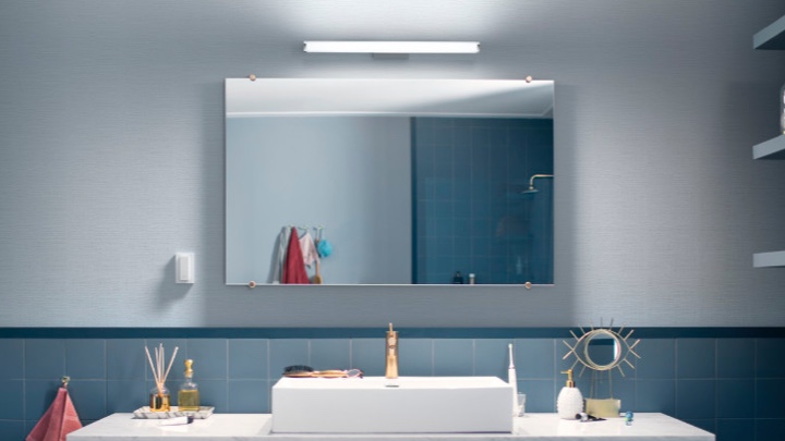 Wandlamp boven een spiegel in de badkamer